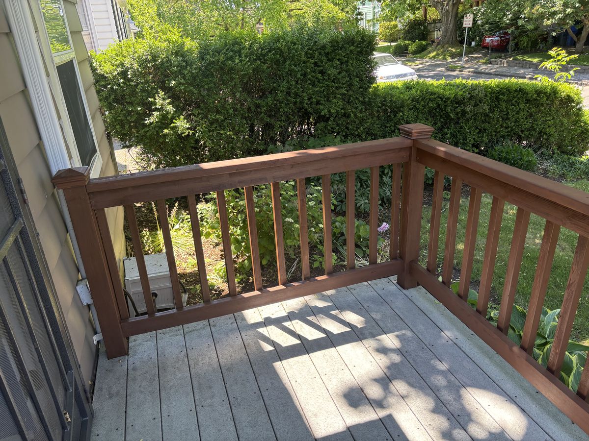 Freshly stained cedar deck railing with square balusters on a front porch